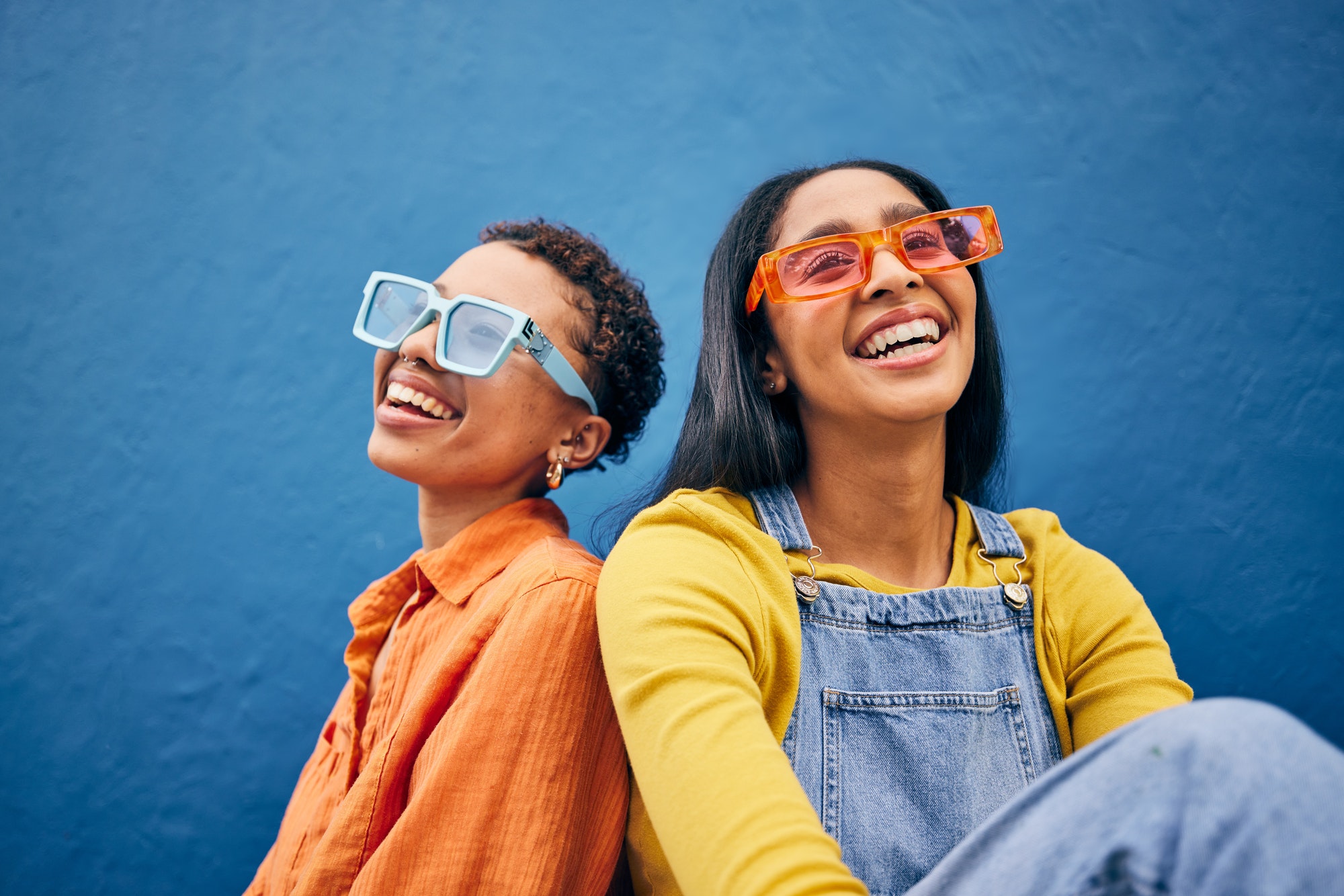 Sunglasses, fashion and women on blue background in city with trendy clothes, accessories and style